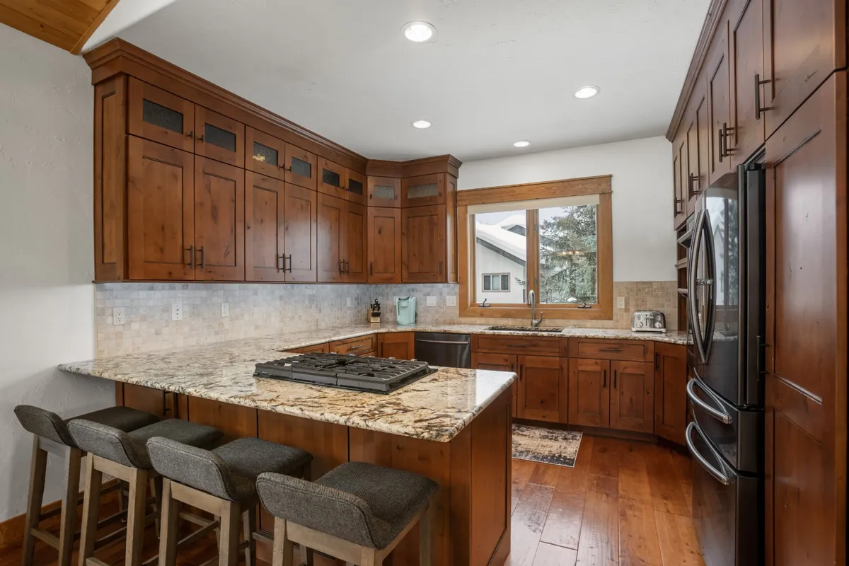 A chef’s kitchen with granite countertops, stainless steel appliances, a central island, and ample wood cabinetry. Large windows fill the space with light, making it both functional and inviting for cooking, entertaining, and casual dining.